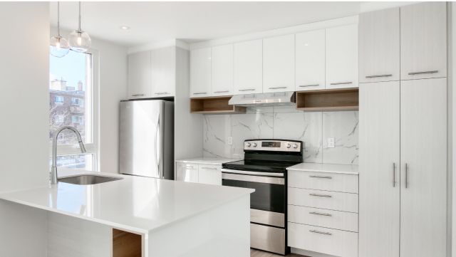 An image of a white kitchen with brand-new metal silver appliances.
