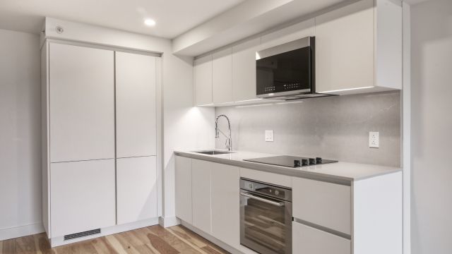 An image of a white kitchen with brand-new, spotless appliances.