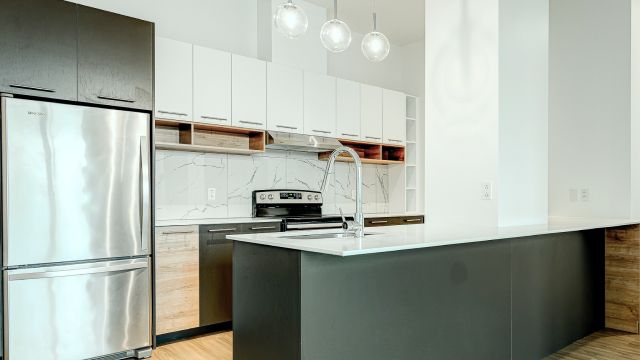 An image of a white kitchen with brand-new metal silver appliances.