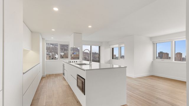 A large white space with numerous windows features a central kitchen table with appliances.