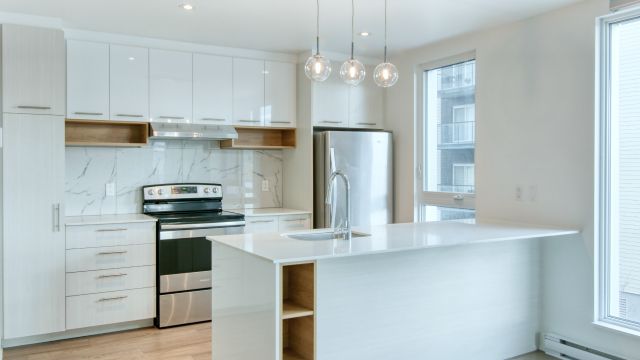 An image of a white kitchen with brand-new metal silver appliances.